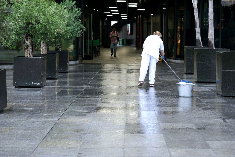 Sprzątaczka myjąca posadzkę w pasażu między budynkami